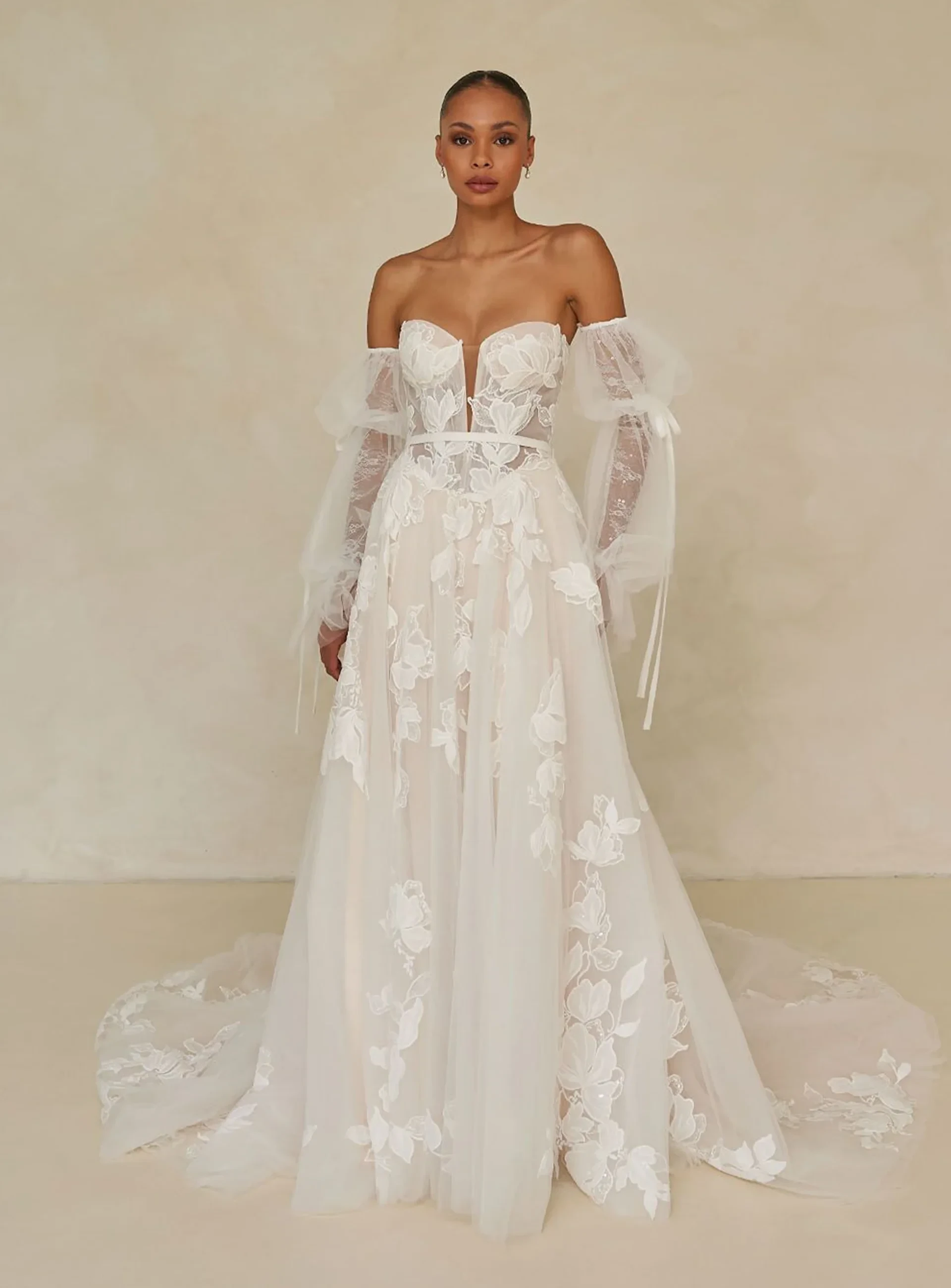 Madi Lane A-line wedding gown with floral lace, sheer bodice, and off-shoulder sleeves.