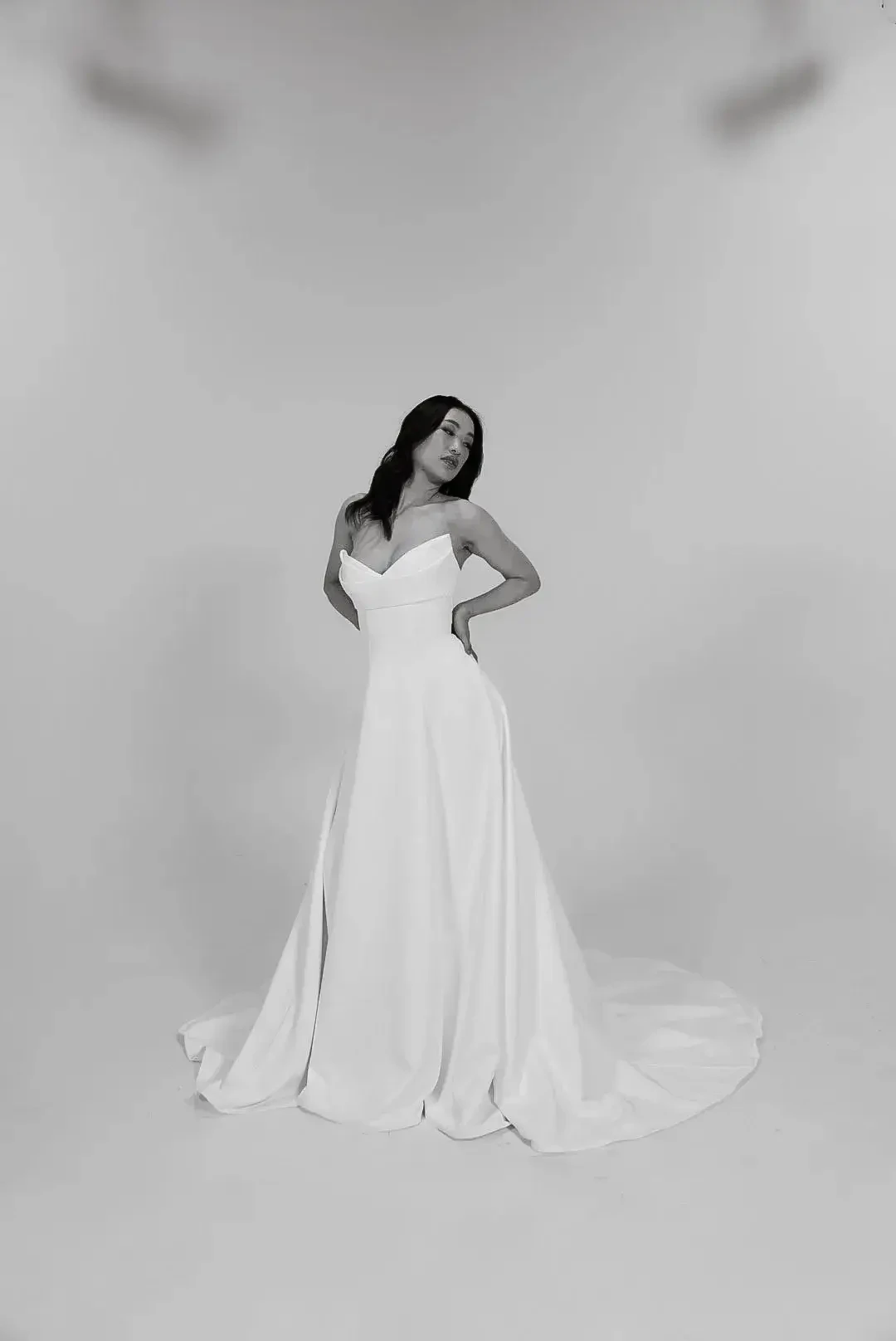 A woman in a white dress posing against a neutral background.