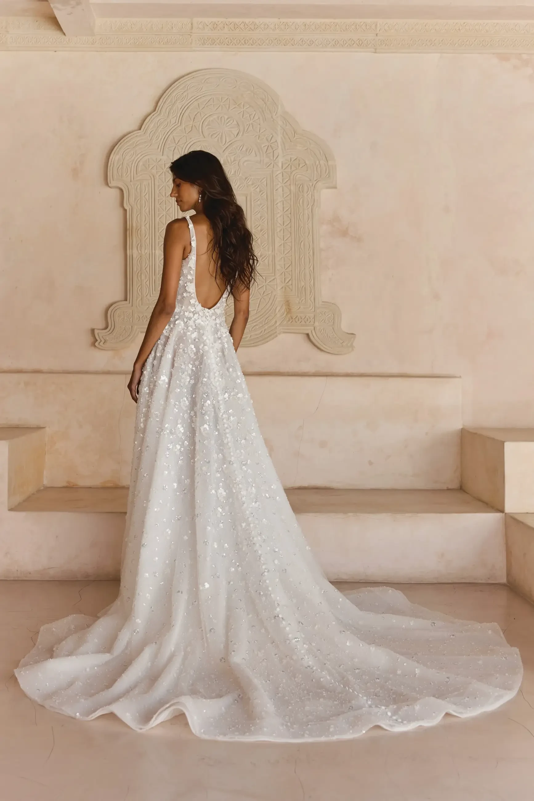 Model is wearing an a-line wedding dress with straps and 3d motifs