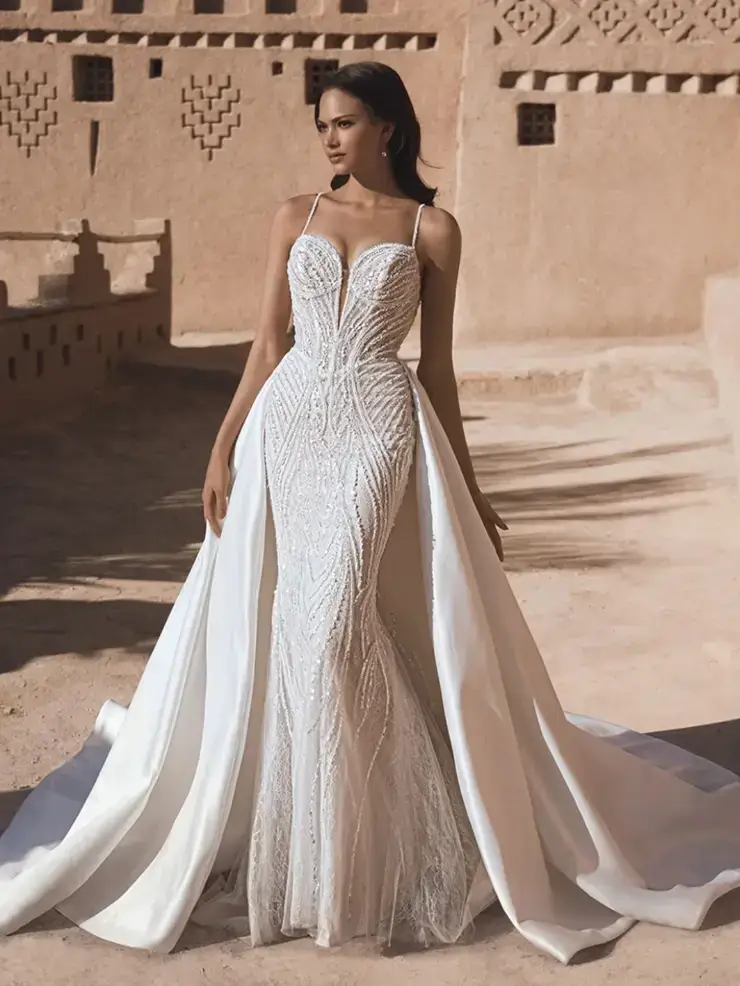 model is wearing a fit and flare wedding dress with an overskirt