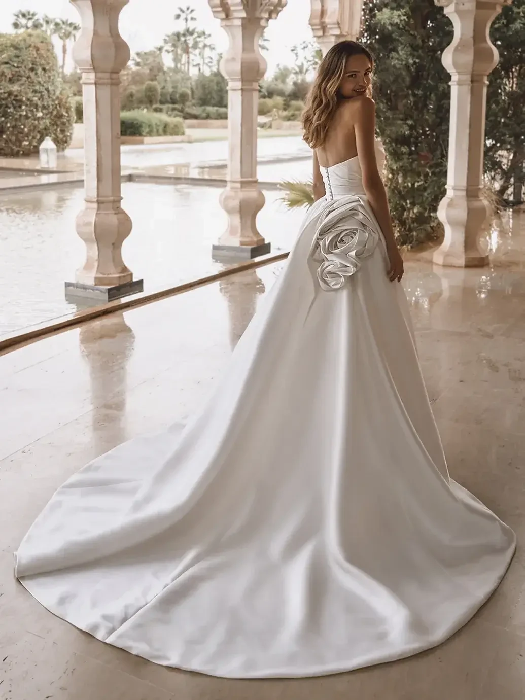 model is wearing a strapless wedding dress with an overskirt