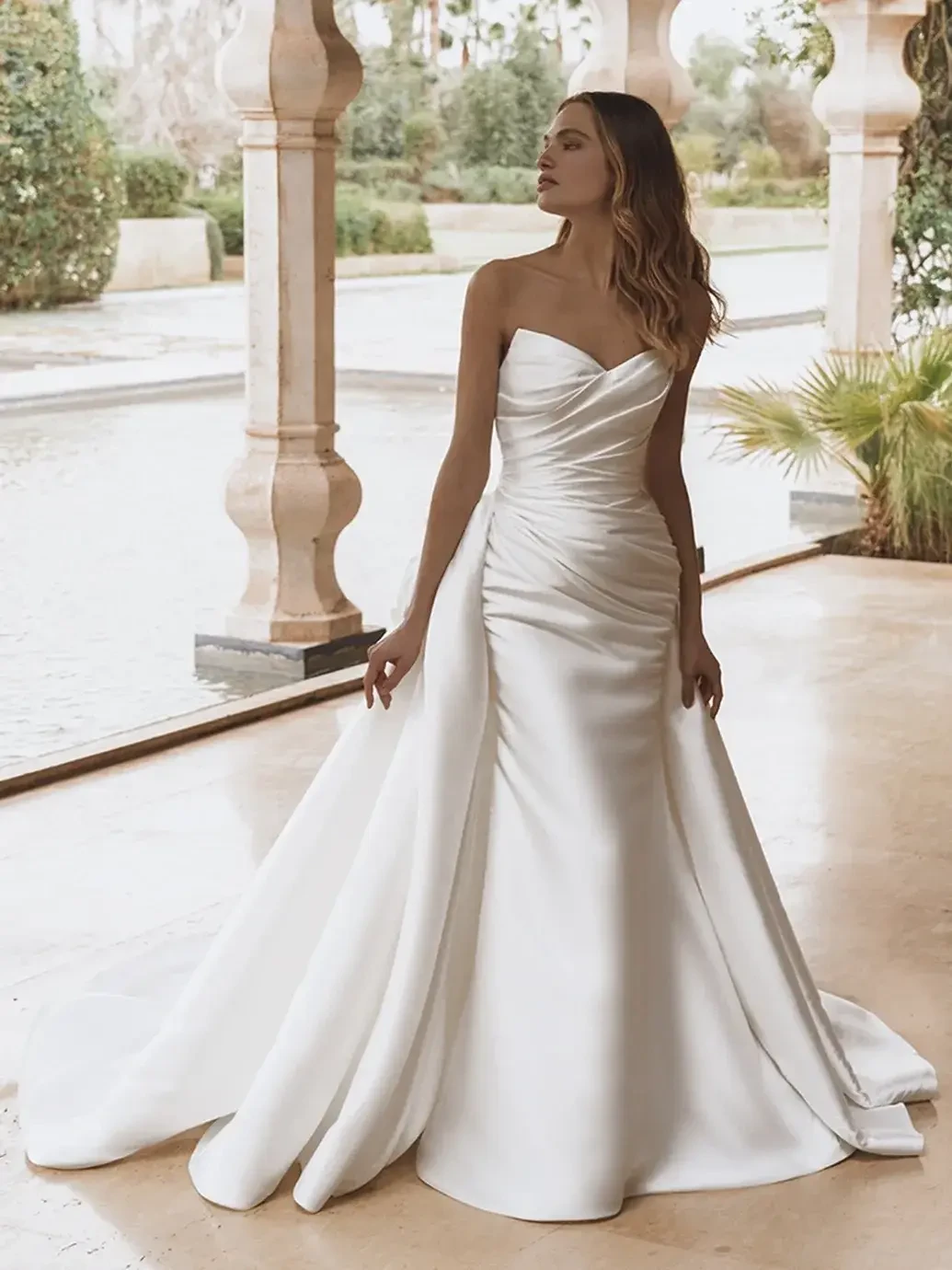 model is wearing a strapless wedding dress with an overskirt